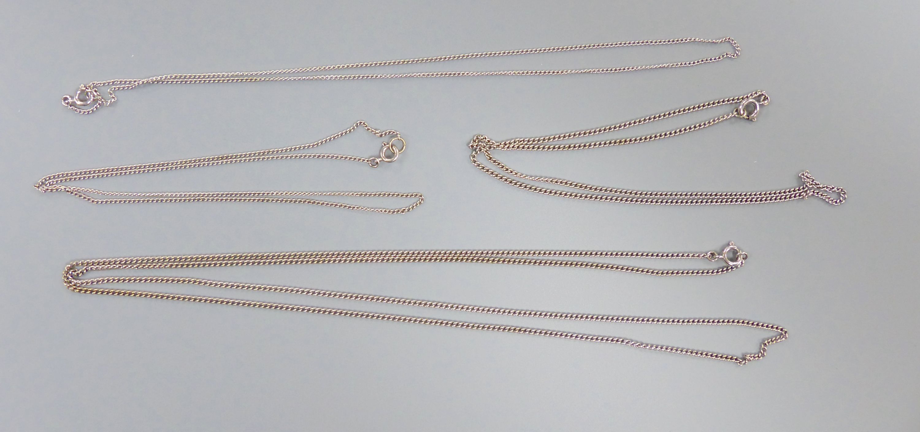 Four assorted white metal finelink chains, stamped 9ct,